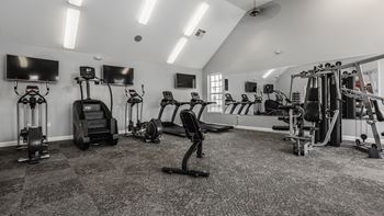 A spacious gym with a variety of equipment including treadmills, stationary bikes, and weight machines